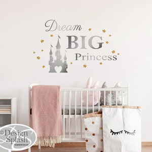 May include: A silver castle silhouette with a heart in the center, surrounded by gold stars. The text "Dream BIG Princess" is written in silver above the castle.