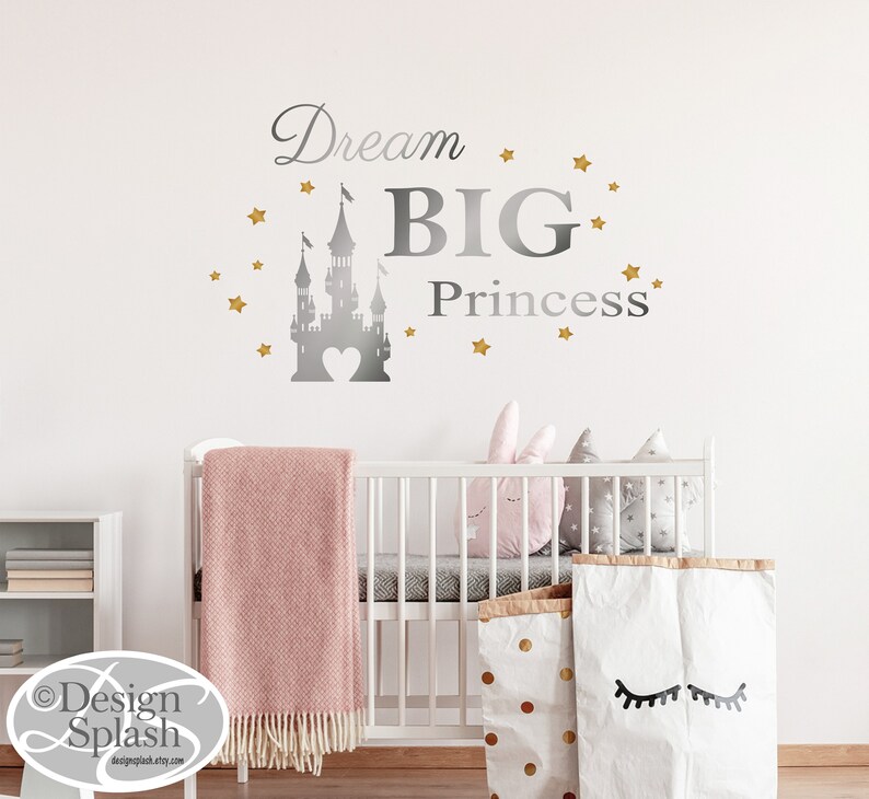 May include: A silver castle silhouette with a heart in the center, surrounded by gold stars. The text "Dream BIG Princess" is written in silver above the castle.