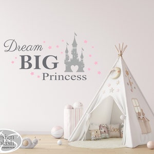 May include: A white teepee tent with pink stars and a crescent moon design. The teepee is set up in a room with a gray wall and a pink and white striped storage bin. A gray castle silhouette with a pink heart is on the wall with the text "Dream BIG Princess" in gray.