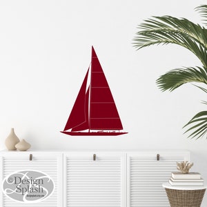 May include: A maroon sailboat silhouette wall decal. The decal is on a white wall with a white cabinet and a potted palm plant in the background.