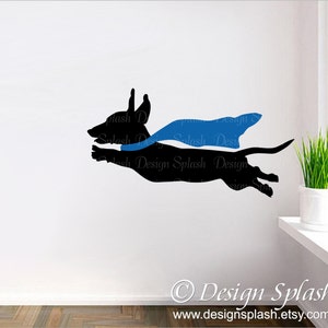 May include: Black silhouette of a dachshund wearing a blue cape, flying through the air. The image is a wall decal.