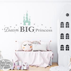 May include: A light green castle silhouette with a heart in the center, surrounded by small silver stars. The text "Dream BIG Princess" is written below the castle in gray.