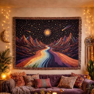May include: A woven tapestry depicting a colourful landscape with a rainbow river flowing through mountains under a starry night sky. The tapestry has a fringed border and is displayed above a purple sofa with decorative cushions.