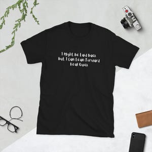 以下が含まれることがあります： 白い文字で「I Might Be Laid Back but I Can Lean Forward Real Quick」と書かれた黒いTシャツ。 このシャツは半袖で、クルーネックです。明るい色の表面に表示されています。