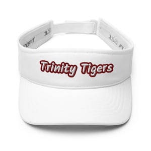 May include: A white visor with the embroidered text "Trinity Tigers" in maroon. The visor has an adjustable strap and a curved brim to shield the eyes from the sun. The visor is a sporty accessory.