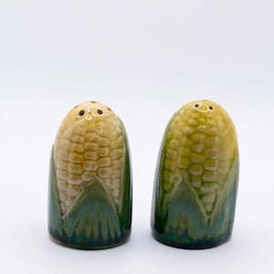 May include: A white ceramic mug with a black handle and the text "But First, Coffee" in a black, handwritten-style font. The mug is on a white surface.