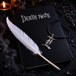 May include: A black notebook with the words DEATH NOTE printed in white on the cover. A white feather quill rests diagonally across the notebook. A silver-colored letter L pendant hangs from a black cord necklace placed on the notebook cover.