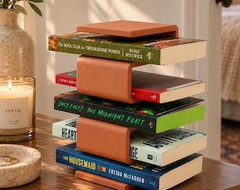 Peut inclure: Un porte-livres en métal de couleur terre cuite au design modulaire, contenant quatre livres empilés dont The Book Club for Troublesome Women, The Midnight Feast et The Housemaid, avec une finition mate lisse et des supports en U.
