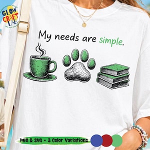 May include: White t-shirt with the phrase "My needs are simple." in black and green. The design includes a green coffee cup, a paw print, and two green books. The shirt also has the text "PNG & SVG • 3 Color Variations."