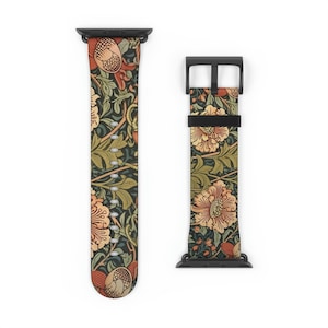 May include: A watch band featuring a dark background with a repeating pattern of orange and peach-colored flowers, green leaves, and brown acorn-like shapes. The band includes a black metal connector and a black buckle with a matching strap loop.