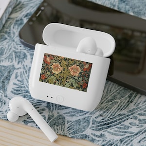 May include: A white wireless earbud charging case with an open lid, featuring a rectangular floral print with orange flowers and green foliage on the front. One white earbud rests outside the case, and another is visible inside the open compartment.