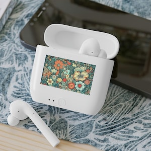 May include: A white wireless earbud charging case with an open lid and a rectangular floral print on the front. The print features orange, yellow, and teal flowers. One white earbud rests inside the case, and another sits on the surface.
