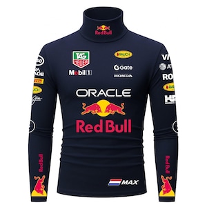 Könnte beinhalten: Marineblaues Langarm-Rollkragenshirt mit verschiedenen Logos, darunter "Red Bull" und "Oracle". Das Shirt zeigt ein großes "Red Bull"-Logo auf der Vorderseite und den Ärmeln sowie weitere Sponsorenlogos. Das Shirt hat einen hohen Kragen.