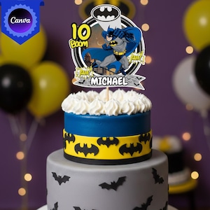 Peut inclure: Un gâteau à deux étages avec une décoration sur le thème de Batman portant les inscriptions 10, Boom, Bam et Michael. L'étage supérieur est bleu avec une bande jaune ornée de silhouettes de chauves-souris noires, et l'étage inférieur est gris.