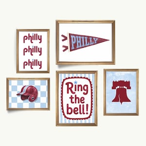 May include: Five framed prints with gold frames. The prints feature baseball-themed designs, including a pennant that says "PHILLY", a baseball helmet, and the Liberty Bell. The words "Philly" and "Ring the bell!" are also displayed.