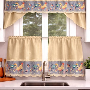 Op de afbeelding: Beige keuken gordijnen met een geborduurd ontwerp van hanen en bloemen. De gordijnen omvatten een valance en twee panelen. De geborduurde rand toont hanen in rood, geel en blauw, met bloemmotieven op een grijze achtergrond.