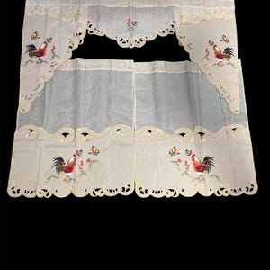 May include: Cream-colored kitchen curtains with a rooster and butterfly design. The curtains have a scalloped edge and embroidered details. The rooster is red, black, and yellow, with butterflies in shades of yellow and orange.