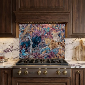 Puede incluir: Un colorido protector contra salpicaduras de cocina con una escena de la jungla que representa un jaguar, pájaros y otros animales. La obra de arte está colocada sobre una estufa de gas de acero inoxidable con perillas de latón. Los gabinetes circundantes son de madera oscura y la encimera es de mármol.