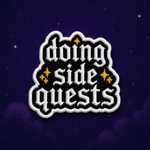 May include: Embroidered patch with the words "doing side quests" in white gothic lettering on a black background. The patch has a white border and gold star accents, set against a dark blue starry sky.