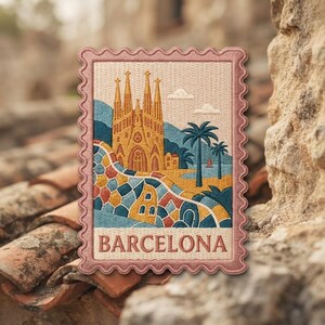 May include: A rectangular embroidered patch shaped like a postage stamp with a scalloped border. The design features the Sagrada Familia in gold, a colorful mosaic wall, palm trees, and the word BARCELONA in capital letters at the bottom.