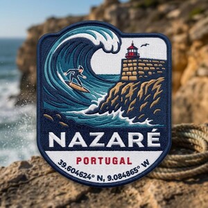 May include: A rectangular embroidered patch with rounded top corners featuring a surfer on a large blue wave, a lighthouse on a tan cliff, and the text NAZARÉ PORTUGAL 39.604624° N, 9.084865° W in white and red lettering against a dark blue border.