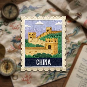 May include: A rectangular embroidered patch shaped like a postage stamp featuring the Great Wall of China in yellow and tan, surrounded by green hills and a light blue sky with white clouds. The word CHINA is printed in white on a dark blue base.