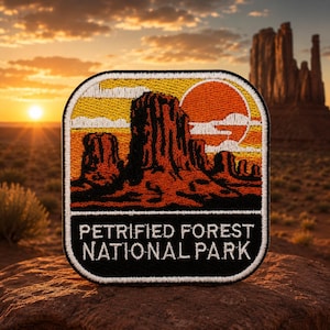 May include: Embroidered patch featuring a desert landscape with a sunset and the text "PETRIFIED FOREST NATIONAL PARK." The patch has a black border and a detailed design of rock formations and a setting sun.