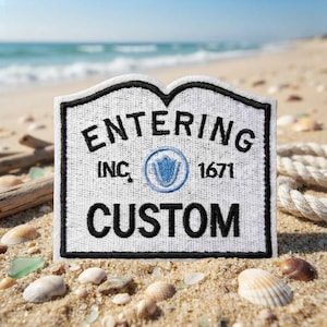 May include: A white embroidered patch with a black border, featuring the black text ENTERING, INC., 1671, and CUSTOM. A small blue circular emblem with a central shield design is positioned between the text. The patch has a curved top edge.