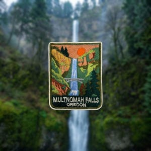 May include: A rectangular embroidered patch featuring a landscape of Multnomah Falls in Oregon. The design includes a tall waterfall, a stone bridge, green pine trees, and a bright orange sun against a peach-colored sky, with the text MULTNOMAH FALLS OREGON.