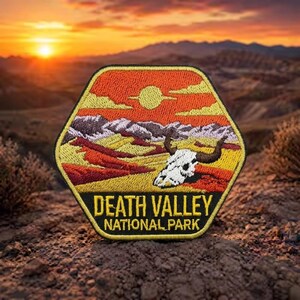 May include: A hexagonal embroidered patch featuring a desert landscape with a white steer skull, yellow and orange terrain, and a sun in the sky. The black bottom section contains the yellow text DEATH VALLEY NATIONAL PARK in capital letters.