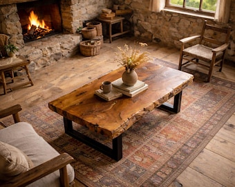 Puede incluir: Un salón rústico con una gran mesa de centro de madera de borde natural y patas de metal negro. Una alfombra estampada, una chimenea de piedra con fuego y sillas de madera completan el ambiente acogedor. Un jarrón con flores secas está sobre la mesa.