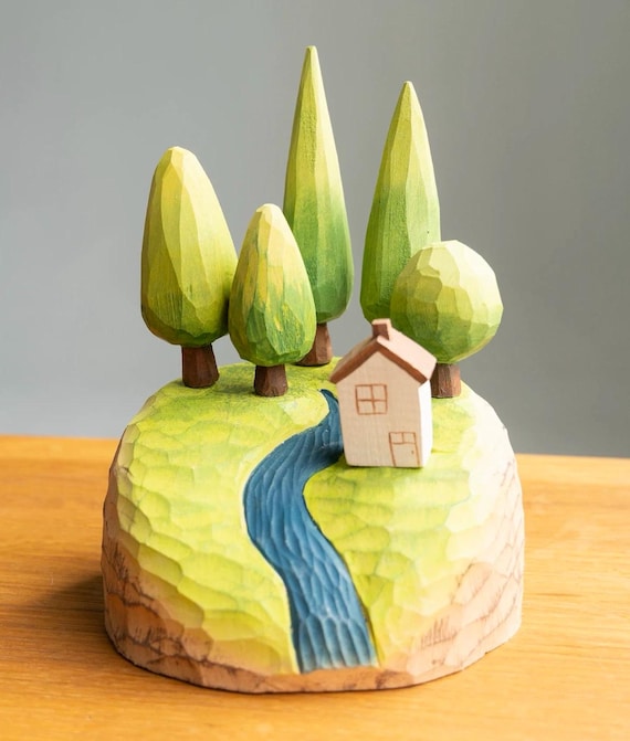 A hand-carved miniature forest scene complete with cabin and trees that snaps together magnetically — like a tiny world a craftsperson built just for your desk.