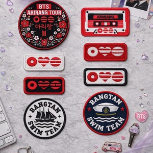 May include: A collection of embroidered patches and accessories, including a round patch with "BTS ARIRANG TOUR" text and floral design, a cassette tape patch, and heart-shaped patches. Other items include a keychain, a photo, and a light stick.