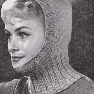 Könnte beinhalten: Nahaufnahme einer Frau, die einen grauen gestrickten Kapuzen-Schal trägt. Der Schal ist mit einer einfachen Strickmasche gearbeitet und hat einen langen Hals.