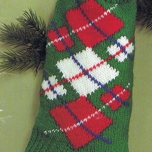 May include: A green knitted Christmas stocking with a red and white diamond pattern. The stocking is filled with a red and white candy cane and a red gift box with white polka dots.