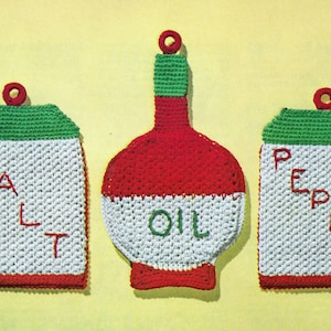 May include: Three crocheted kitchen items: a red and white oil bottle, a red and white salt container, and a red and white pepper container. Each item has a green crocheted top and a red crocheted bottom.