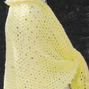 May include: A woman wearing a wide-brimmed straw hat with a crocheted design and a yellow crocheted shawl. She is wearing a white shirt with a polka dot pattern.
