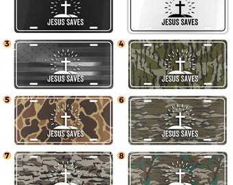 May include: License plates with the text "JESUS SAVES" and a cross design. The plates feature various backgrounds, including black, white, camouflage, and an American flag design. The text and cross are white.