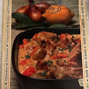 May include: A vintage cookbook titled "Woman's Day Encyclopedia of Cookery, Vol. 3." The cover features a close-up of a cooked dish with meat and vegetables. The book's border lists various cookbook categories, including "Chicken," "Chocolate," and "Cheese."