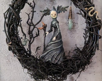 Black Wreath with Raven Witch figure holding a sickle staff in a wicked garden complete with a snake and spider.