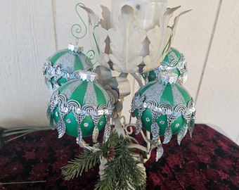 Green and silver Christmas ornaments with ornate trim with feathery dangles.