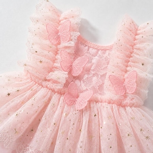 Puede incluir: Vestido rosa claro con falda de tul y corpi&ntilde;o de encaje. El vestido est&aacute; adornado con detalles de estrellas doradas y mariposas rosas bordadas. Tiene mangas con volantes y cuello redondo. El vestido est&aacute; dise&ntilde;ado para una ni&ntilde;a.