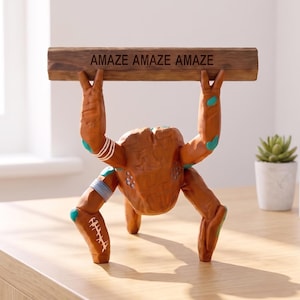 Peut inclure: Une figurine humanoïde brune et texturée avec des accents sarcelle et des marques blanches, debout sur quatre membres tout en tenant une barre en bois horizontale au-dessus de sa tête. La barre porte le texte "AMAZE AMAZE AMAZE" gravé.