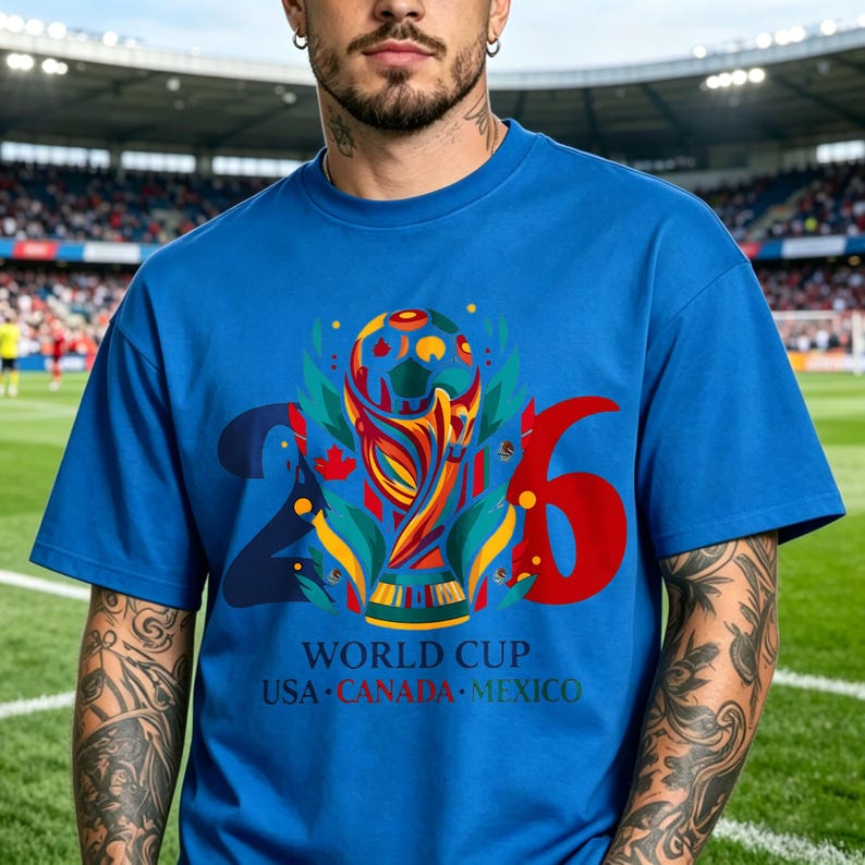 Puede incluir: Una camiseta azul brillante de manga corta con un gr&aacute;fico grande del trofeo de la Copa Mundial 2026 en el centro. El dise&ntilde;o incluye los n&uacute;meros 2 y 6 en azul oscuro y rojo, con el texto WORLD CUP USA CANADA MEXICO impreso debajo.