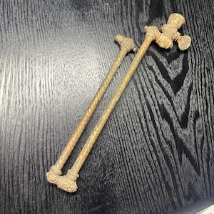 Può includere: Due antichi bulloni in ottone per sponde del letto con finali decorativi. I bulloni hanno un fusto attorcigliato e strutturato e dettagli ornati alle estremità. L'ottone ha un aspetto invecchiato, che suggerisce l'artigianato vintage.