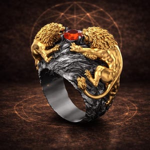 Könnte beinhalten: Ein goldfarbener Ring mit zwei Löwenfiguren, die einen roten Edelstein flankieren. Die Löwen haben detaillierte Mähnen und Körper, gesetzt auf einem dunklen, strukturierten Band. Das Design des Rings ist aufwendig und auffällig.