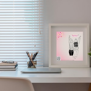 May include: A framed print with the words "Best Friend" and an illustration of two figures embracing. The artwork is in a white frame, set on a white desk with a laptop, pencils, and a stack of books. The background is a window with white blinds.