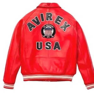 May include: A bright red leather jacket with the text "AVIREX" arched across the shoulders and "USA" below. The jacket features a white and red striped trim on the cuffs and hem. A circular patch with a US flag design is centered on the back.