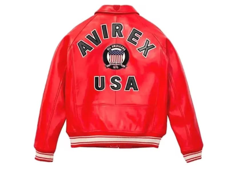 May include: A bright red leather jacket with the text "AVIREX" arched across the shoulders and "USA" below. The jacket features a white and red striped trim on the cuffs and hem. A circular patch with a US flag design is centered on the back.