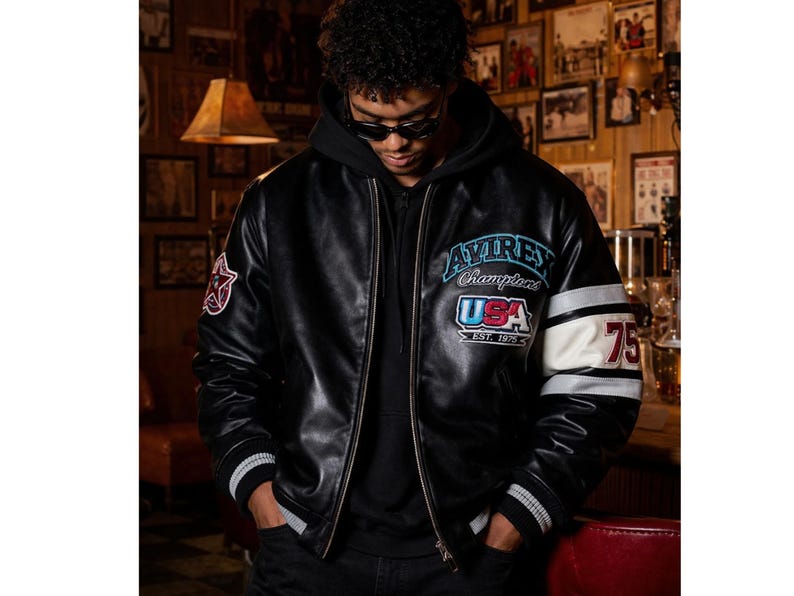 May include: A white ceramic mug with a black handle and the text "But First, Coffee" in a bold, black font. The mug is set against a blurred background, suggesting a cozy setting.